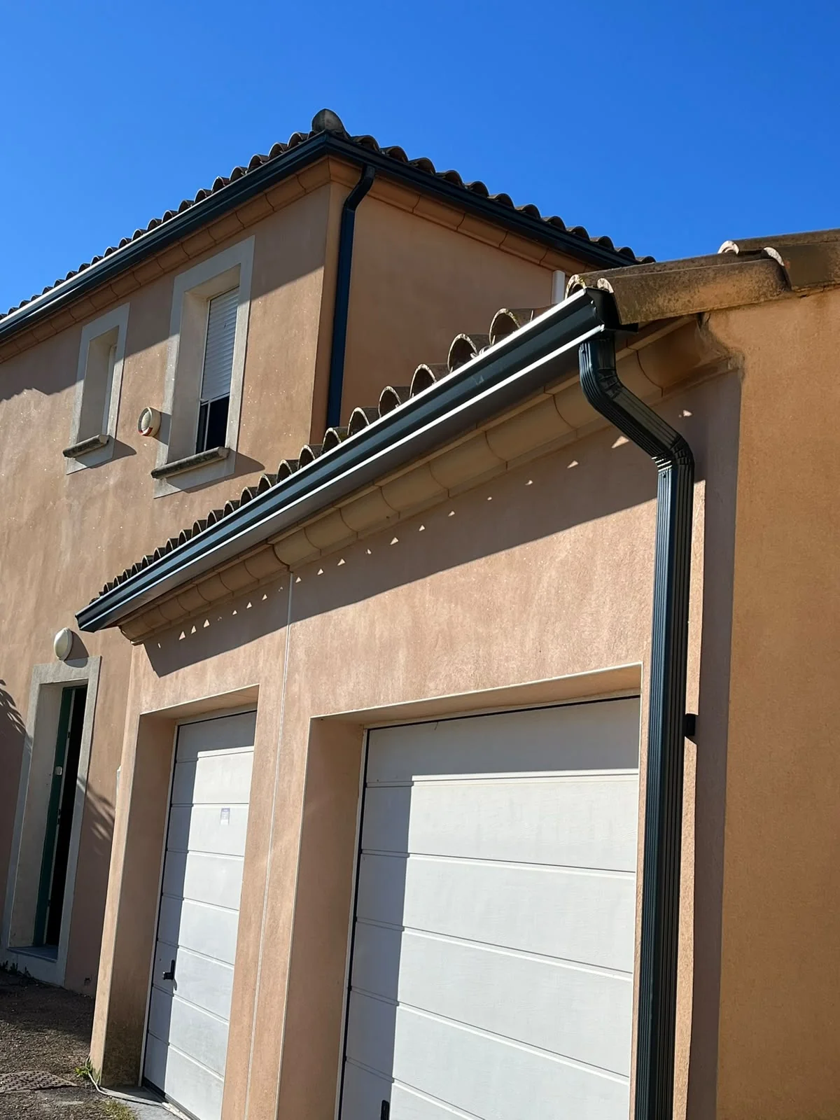 Habillage de débord de toit avec gouttière anthracite sur façade ocre