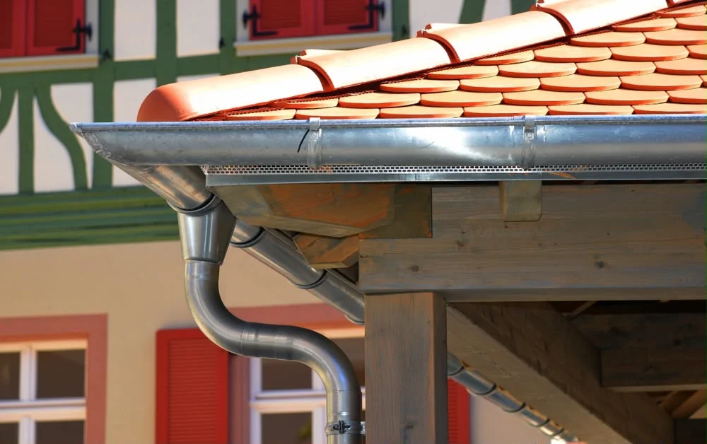 Gouttière zinc demi-ronde avec descente sur maison à colombages